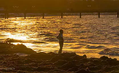 Junge in der Abendsonne am Strand des Ostseebades Binz